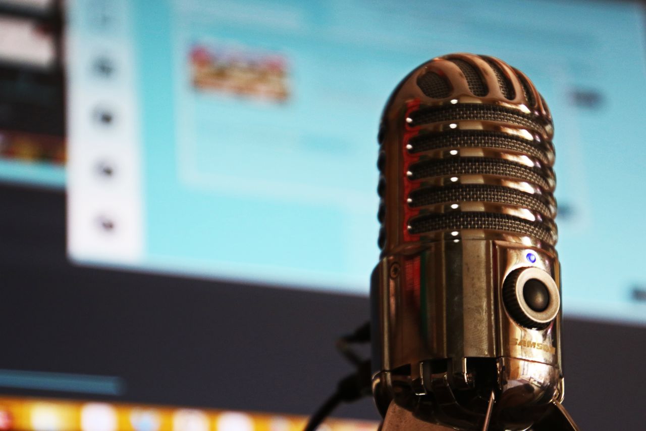 Vintage microphone in focus against a blurred computer screen background.